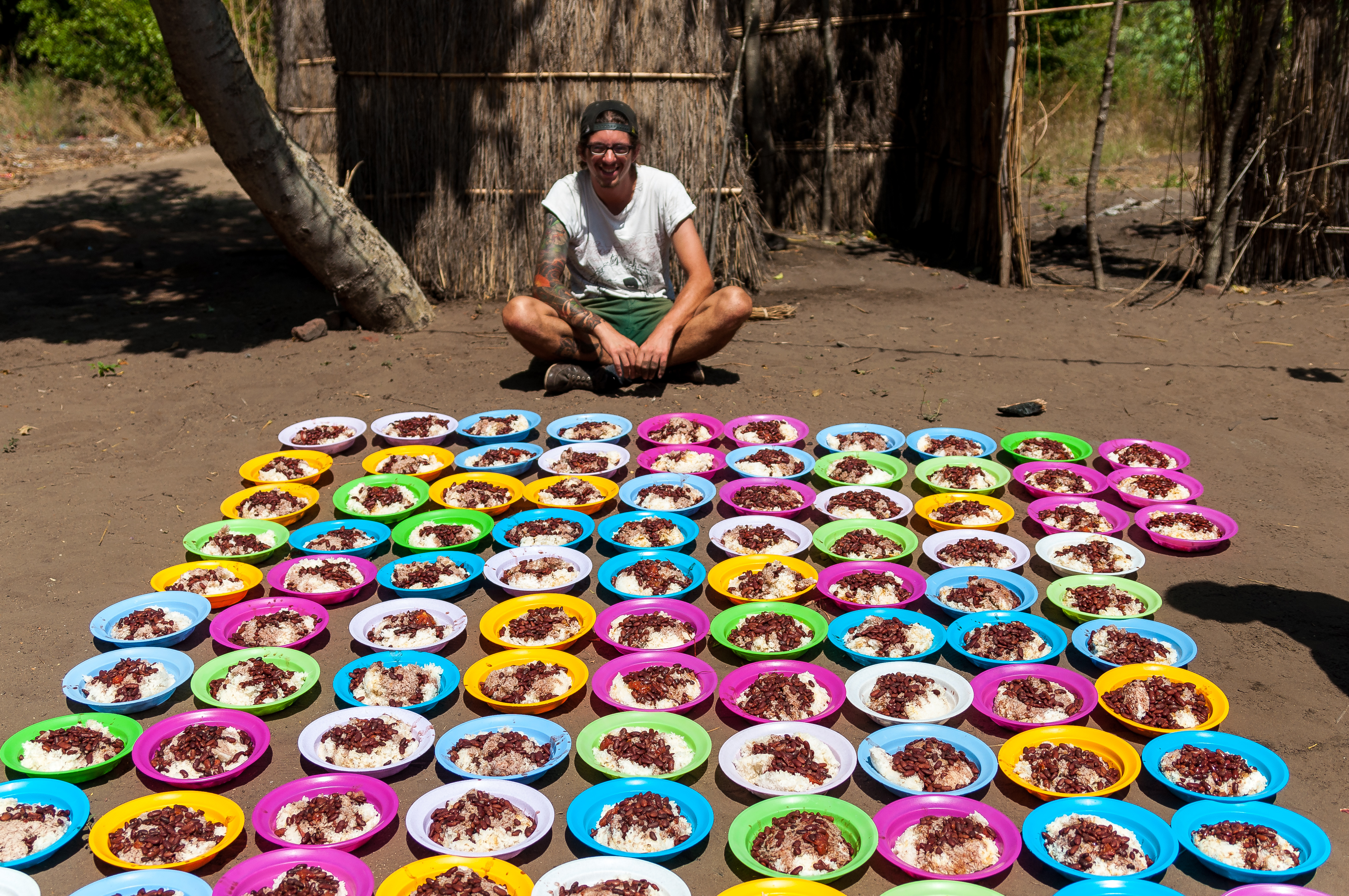 Marvin sits proudly with the 100+ carefully arranged plates of rice and beans.