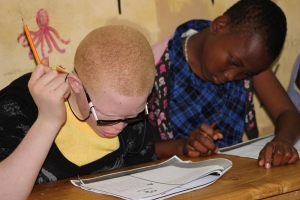 Kids sitting at a desk with pencils in hand.